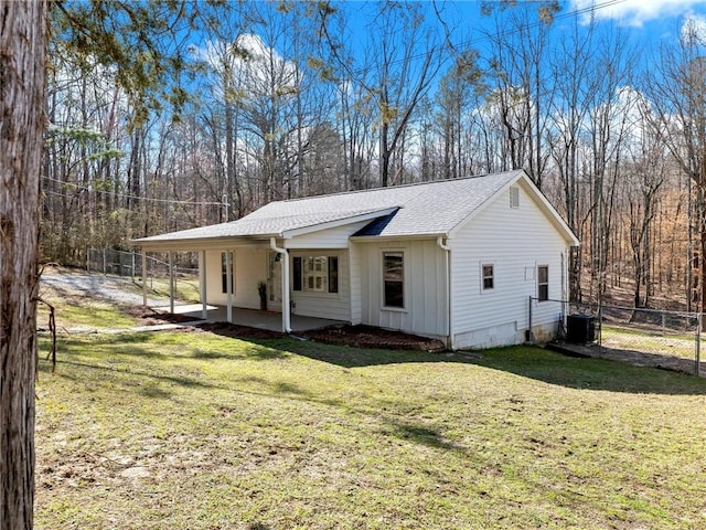 view of front of home with central air condition unit, a shingled roof, a gate, fence, and a front lawn