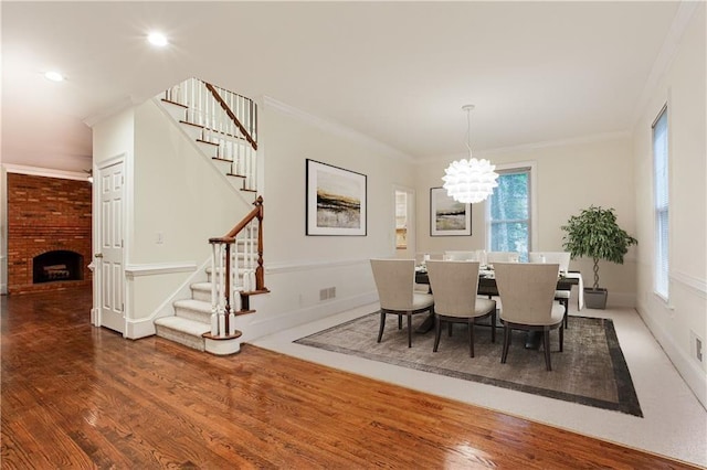 dining room with a notable chandelier, stairway, wood finished floors, and ornamental molding