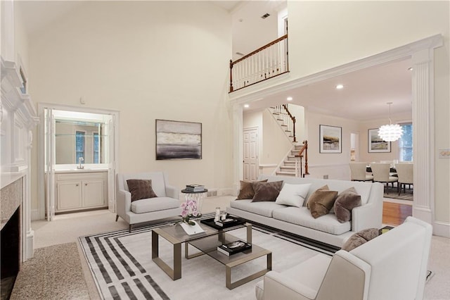 living area featuring light carpet, a notable chandelier, a high ceiling, and stairs