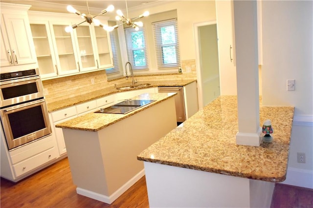 kitchen featuring light stone countertops, light wood-style flooring, a sink, stainless steel appliances, and a center island