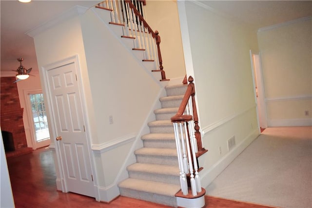 stairs with a ceiling fan, crown molding, visible vents, and baseboards