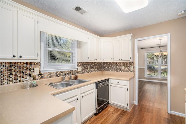 kitchen with sink, hanging light fixtures, hardwood / wood-style flooring, black dishwasher, and white cabinetry