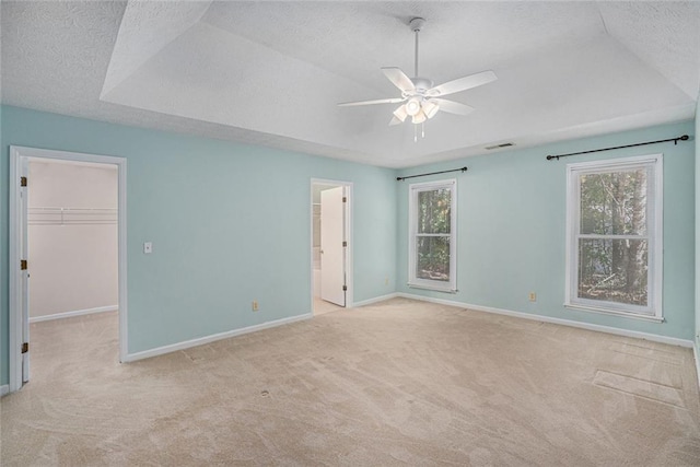 unfurnished bedroom featuring ceiling fan, a spacious closet, a textured ceiling, light colored carpet, and a closet