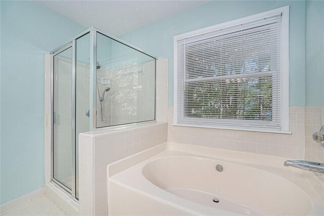 bathroom with plus walk in shower, a textured ceiling, and tile patterned flooring