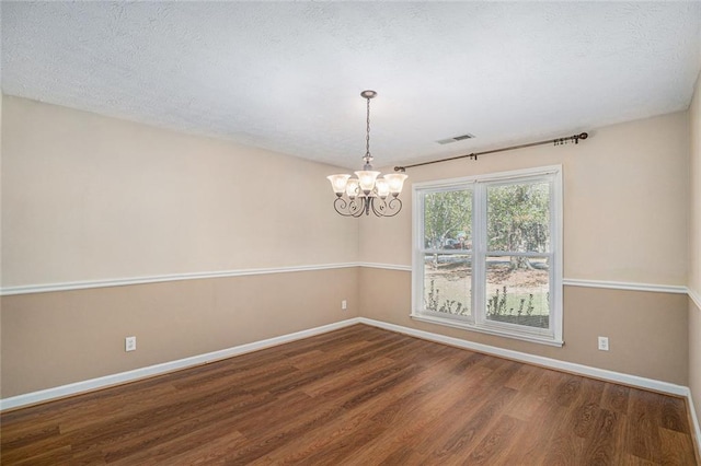 unfurnished room with wood-type flooring, a textured ceiling, and an inviting chandelier