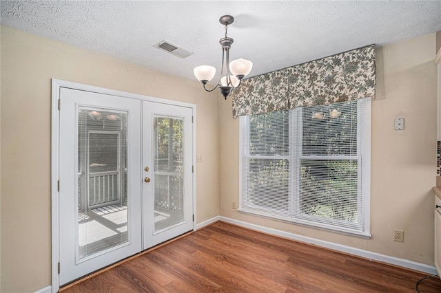 entryway featuring hardwood / wood-style flooring, a chandelier, a textured ceiling, and french doors