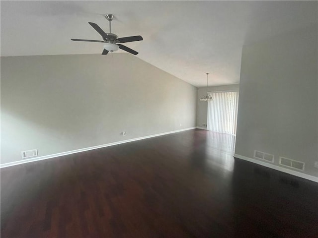 empty room featuring ceiling fan with notable chandelier, lofted ceiling, and dark wood-type flooring