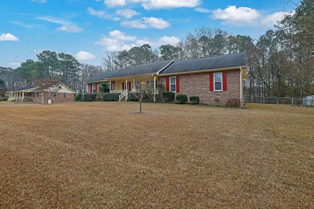 ranch-style home featuring covered porch and a front yard