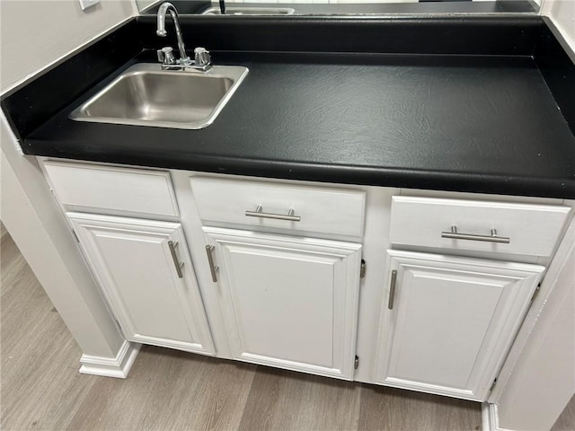 room details featuring white cabinetry, sink, and hardwood / wood-style floors