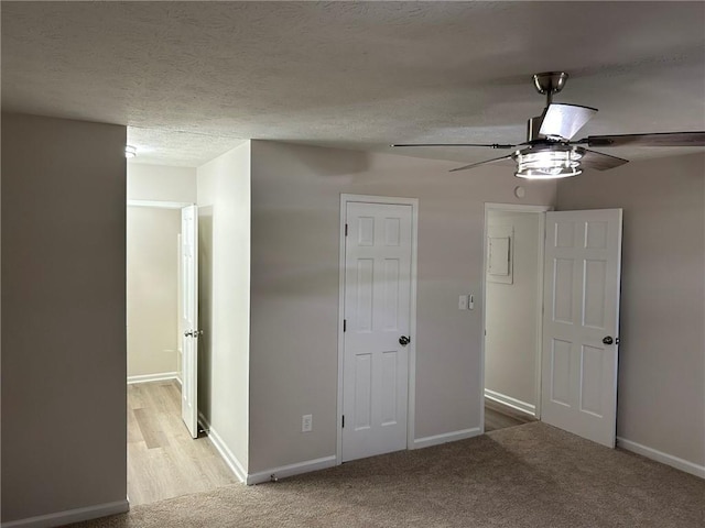 unfurnished bedroom with ceiling fan, light colored carpet, and a textured ceiling