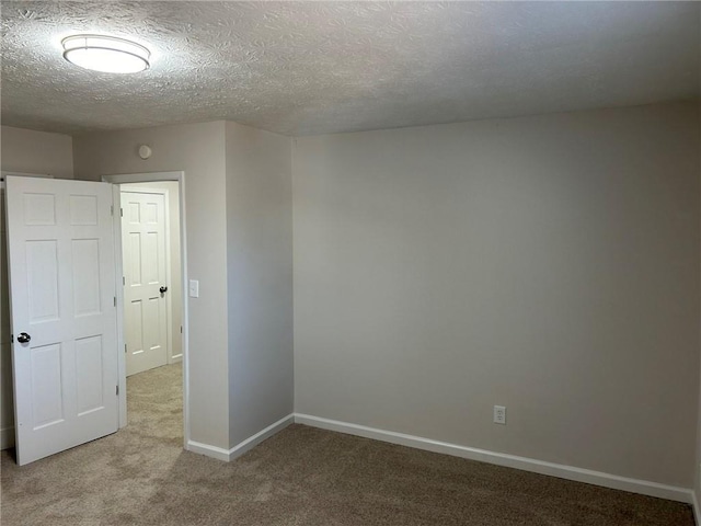 empty room with light colored carpet and a textured ceiling