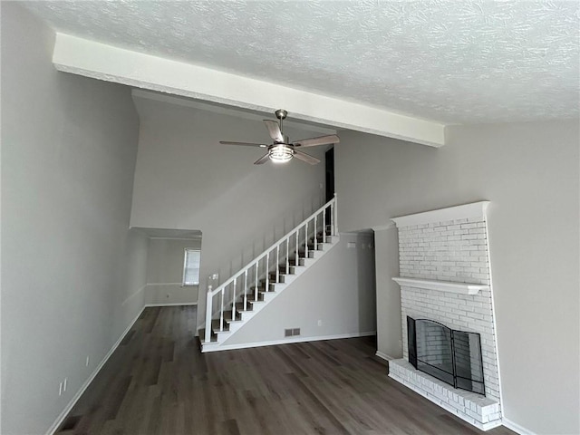 unfurnished living room featuring vaulted ceiling with beams, a textured ceiling, dark hardwood / wood-style floors, ceiling fan, and a fireplace