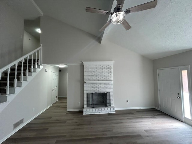 unfurnished living room with a brick fireplace, dark wood-type flooring, vaulted ceiling with beams, and ceiling fan