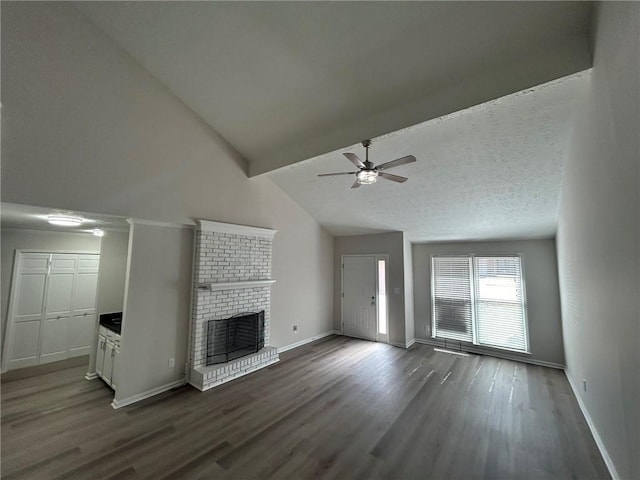 unfurnished living room featuring dark wood-type flooring, ceiling fan, beam ceiling, a textured ceiling, and a brick fireplace