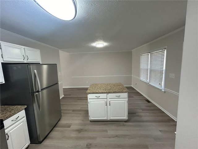 kitchen with white cabinetry, hardwood / wood-style floors, stainless steel fridge, and ornamental molding