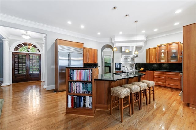 1255 Beech Haven Rd NE, Atlanta, GA 30324 - kitchen featuring stainless steel built in fridge, brown cabinetry, dark countertops, a kitchen island with sink, and crown molding