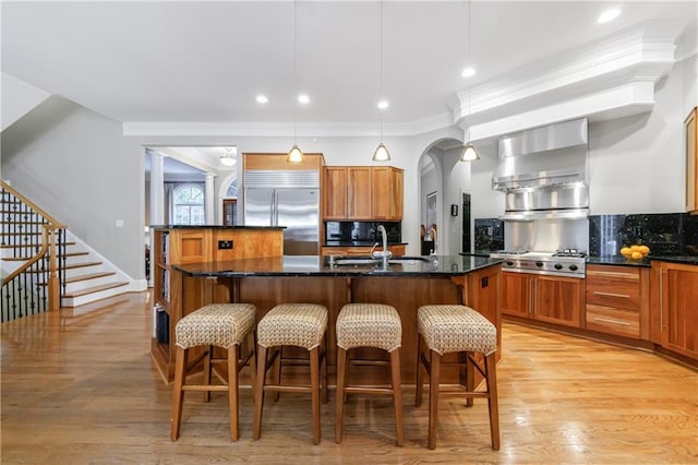 1255 Beech Haven Rd NE, Atlanta, GA 30324 - kitchen featuring stainless steel appliances, a sink, an island with sink, a breakfast bar area, and wall chimney exhaust hood