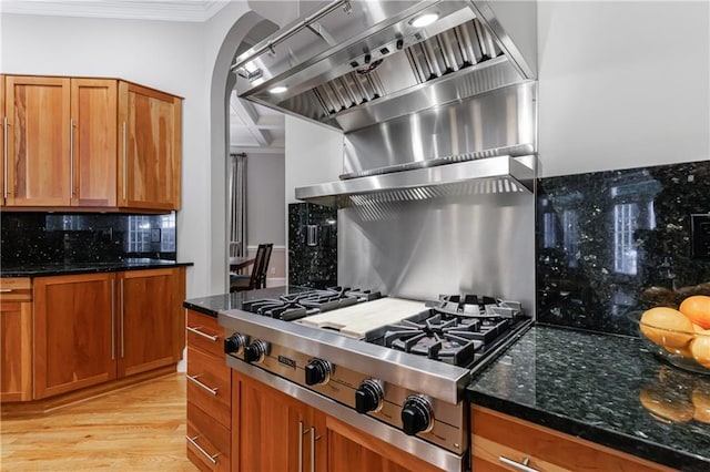1255 Beech Haven Rd NE, Atlanta, GA 30324 - kitchen with stainless steel gas stovetop, decorative backsplash, ornamental molding, wall chimney range hood, and dark stone countertops