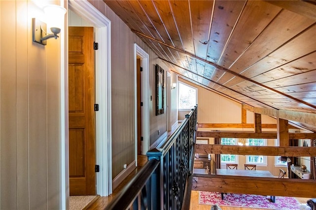 hall featuring vaulted ceiling, wooden ceiling, and wooden walls