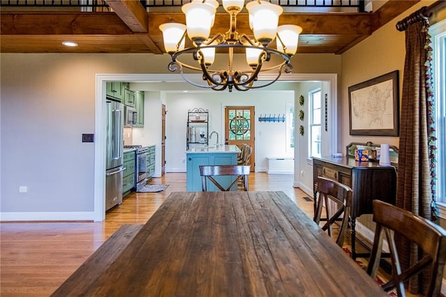 dining area with beamed ceiling, an inviting chandelier, and light hardwood / wood-style floors