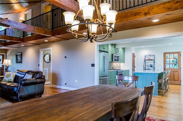 dining area featuring an inviting chandelier, beam ceiling, light hardwood / wood-style floors, and a high ceiling