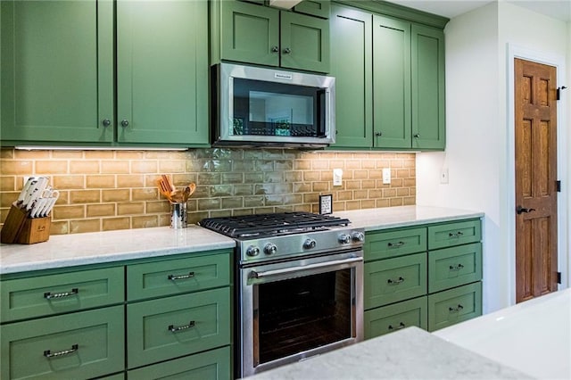 kitchen featuring appliances with stainless steel finishes, decorative backsplash, light stone counters, and green cabinetry