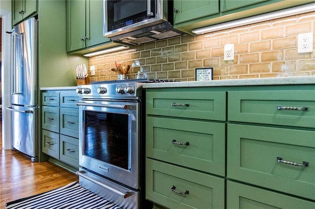 kitchen featuring backsplash, stainless steel appliances, dark hardwood / wood-style floors, and green cabinets