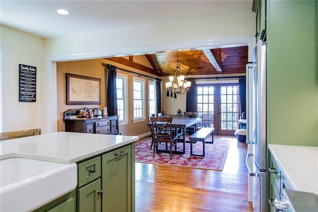 kitchen with french doors, lofted ceiling, hanging light fixtures, green cabinets, and light hardwood / wood-style floors