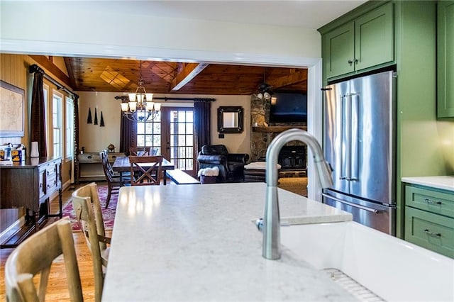 kitchen with high end fridge, sink, hanging light fixtures, wooden ceiling, and green cabinets