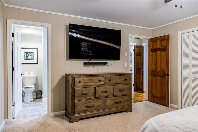 carpeted bedroom with crown molding, ensuite bath, ceiling fan, and a closet