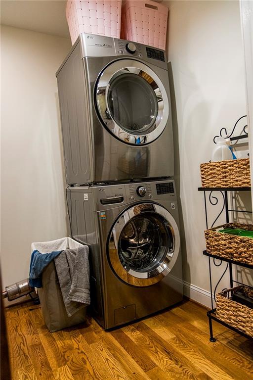 washroom with stacked washer and dryer and light wood-type flooring