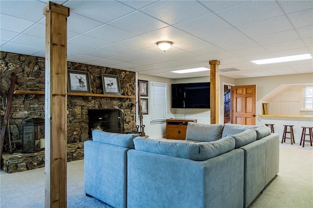 living room featuring light colored carpet, a fireplace, decorative columns, and a drop ceiling