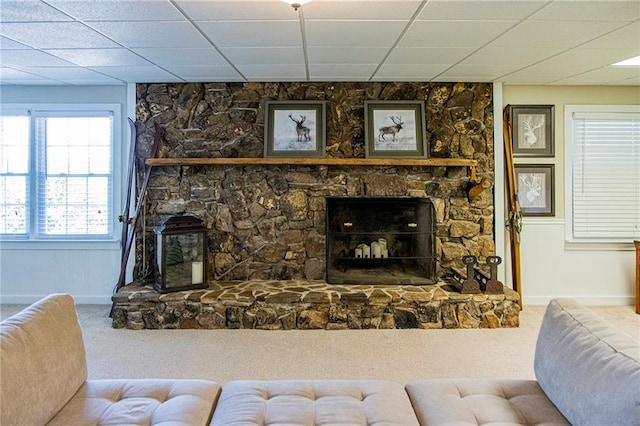 living room with carpet, a drop ceiling, and a fireplace