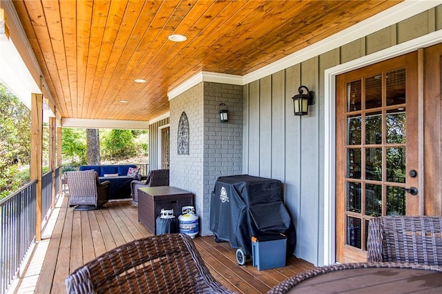 wooden deck with an outdoor hangout area and grilling area