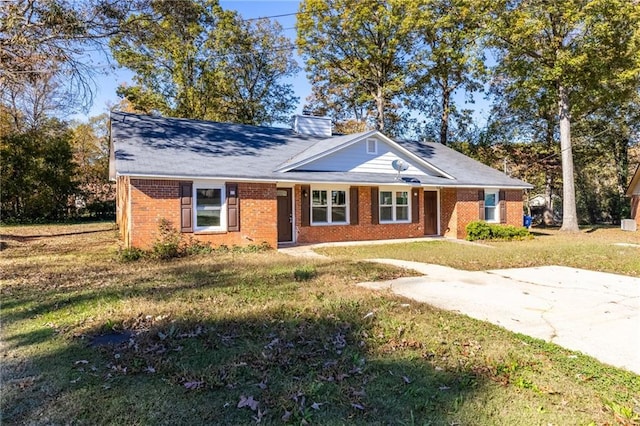 view of front of house featuring a front lawn, brick siding, and a chimney