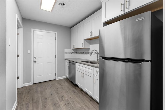 kitchen featuring visible vents, appliances with stainless steel finishes, white cabinetry, and a sink