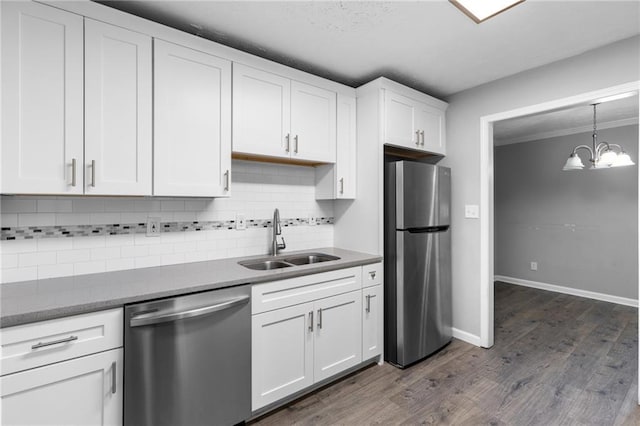 kitchen featuring a sink, backsplash, appliances with stainless steel finishes, white cabinets, and dark wood-style flooring