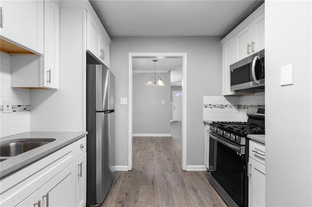 kitchen with dark wood-type flooring, baseboards, decorative backsplash, white cabinets, and stainless steel appliances