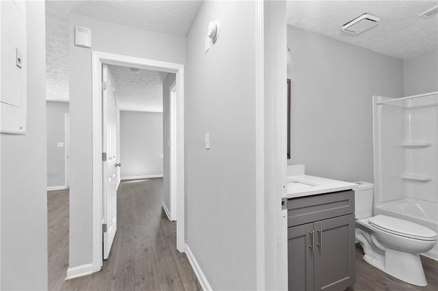 bathroom featuring toilet, wood finished floors, visible vents, and a textured ceiling