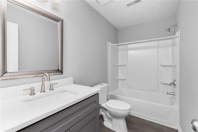 bathroom with visible vents, toilet, a textured ceiling, wood finished floors, and vanity