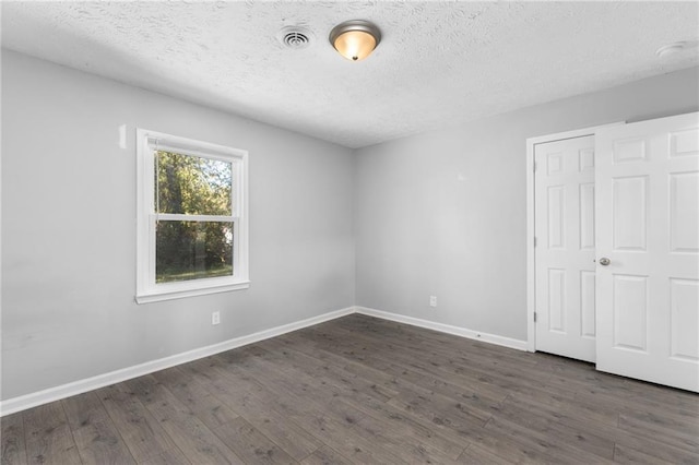 unfurnished bedroom featuring baseboards, dark wood-style flooring, and a textured ceiling