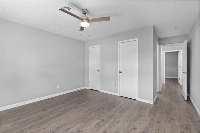 unfurnished bedroom with a textured ceiling, wood finished floors, visible vents, and baseboards