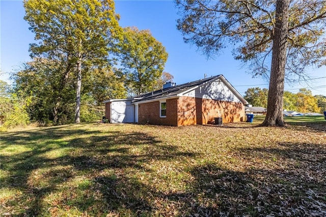 view of side of home featuring solar panels, a yard, and brick siding