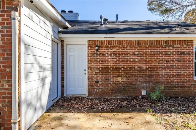 property entrance featuring brick siding and a chimney