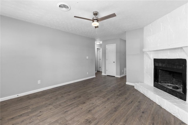 unfurnished living room featuring visible vents, dark wood-type flooring, a textured ceiling, a fireplace, and baseboards