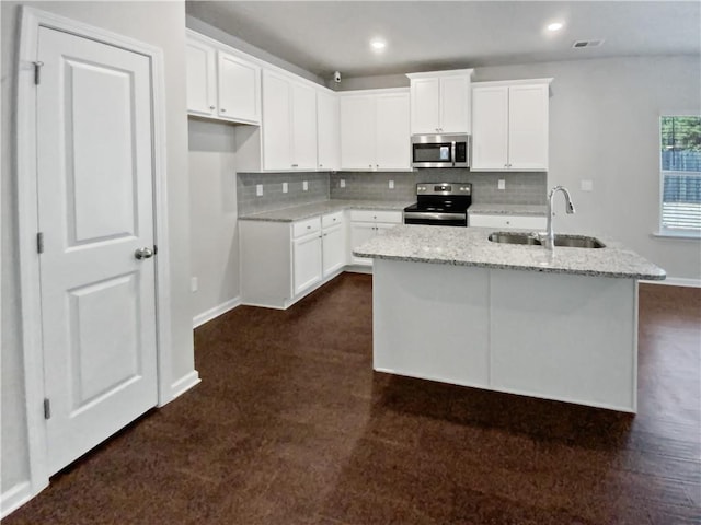 kitchen with light stone counters, a center island with sink, white cabinets, appliances with stainless steel finishes, and sink