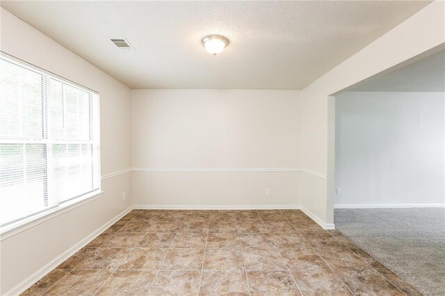 carpeted empty room featuring a textured ceiling