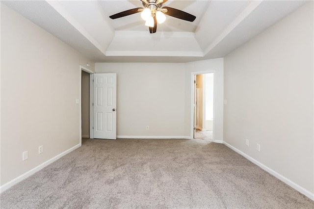 carpeted empty room with ceiling fan and a raised ceiling