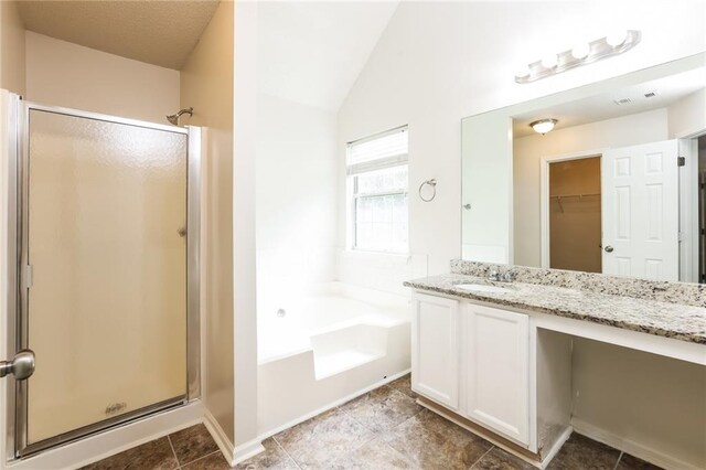 bathroom featuring vanity, independent shower and bath, lofted ceiling, and tile patterned flooring