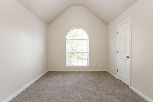 carpeted empty room featuring vaulted ceiling